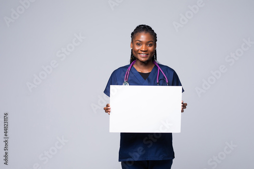 African doctor woman, medical professional working holding blank advertising banner, good poster for ad, offer or announcement, paper billboard.