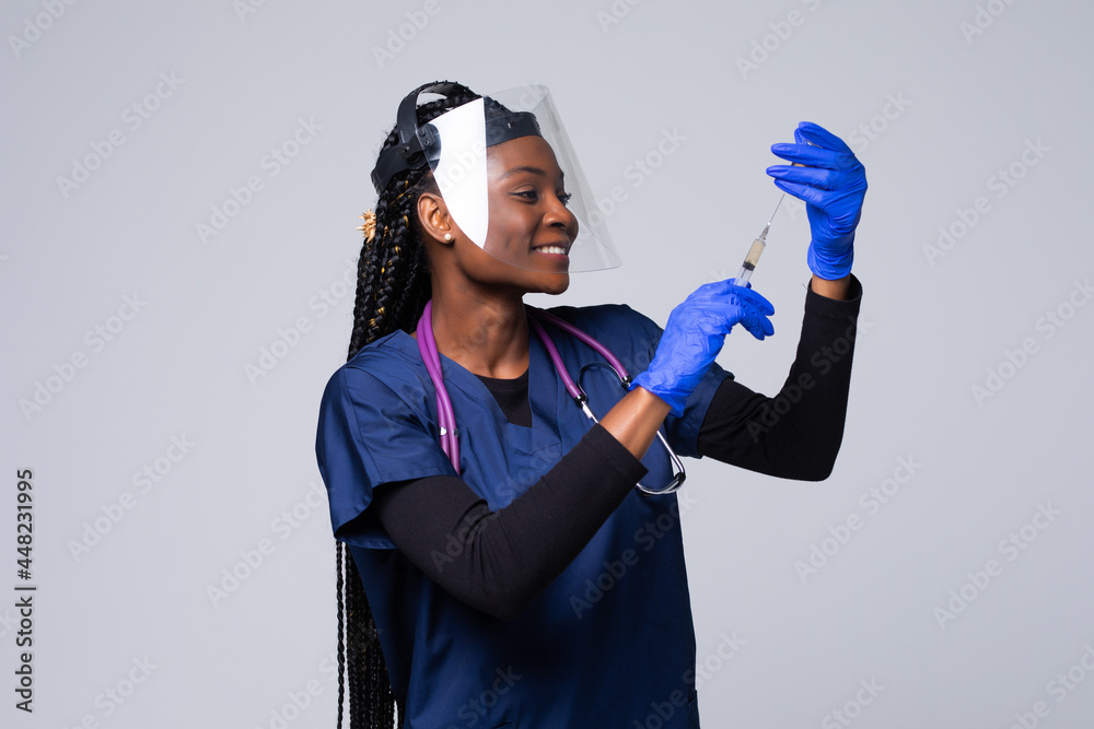 Medicine, vaccination and healthcare concept, African american female doctor or scientist in mask with syringe over grey background Medicine, vaccination and healthcare concept, African american female doctor or scientist in mask with syringe over grey background
