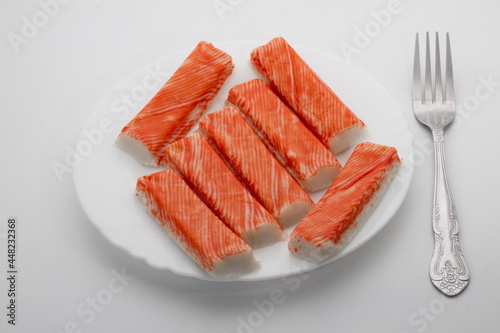 Crab sticks on a white plate with a fork