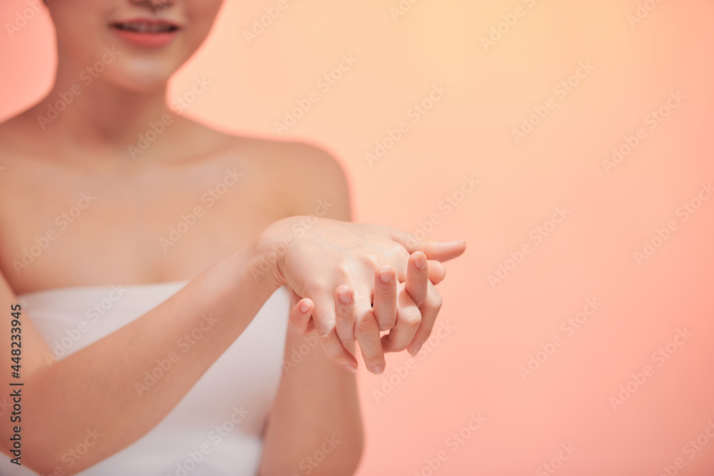 Naklejka premium The girl smears hands with a leaving cosmetic cream for a youth and elasticity of a skin