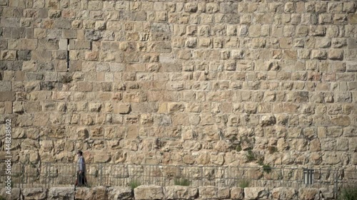 Texture pattern shot of western wall at Jerusalem, Israel. Clean architectural slow motion wide angle shot of people passing by the willing wall. Background bricks panorama concept.