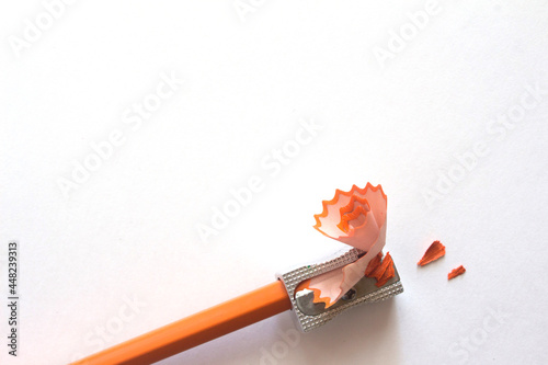 orange pencil with sawdust and sharpener on white. High quality photo