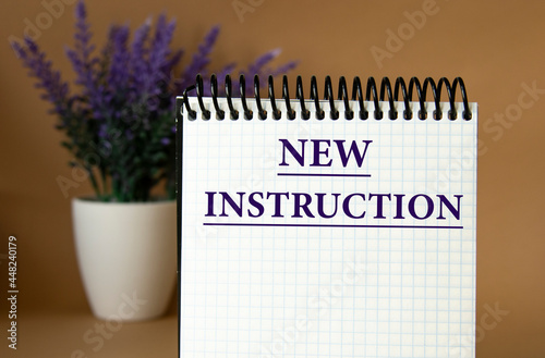 NEW INSTRUCTION - words in a white notebook on a brown background with a bouquet of lavender photo