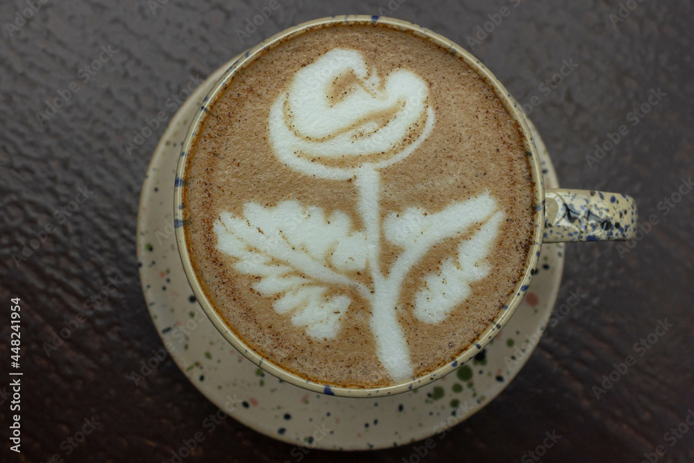 Hot coffee. Drawing on milk foam. Italian restaurant. Beautiful presentation of a coffee drink. Rose on creamy foam. Coffee in a cup top view. Drink decoration. Hot coffee. Drawing on milk foam. Italian restaurant. Beautiful presentation of a coffee drink. Rose on creamy foam. Coffee in a cup top view. Drink decoration.