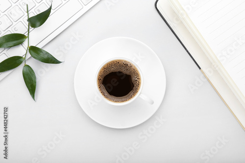 Cup of coffee, notebook and keyboard on grey background