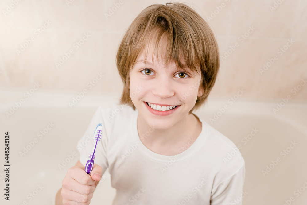 Happy teen boy holding toothbrush and showing his beaming smile Happy teen boy holding toothbrush and showing his beaming smile