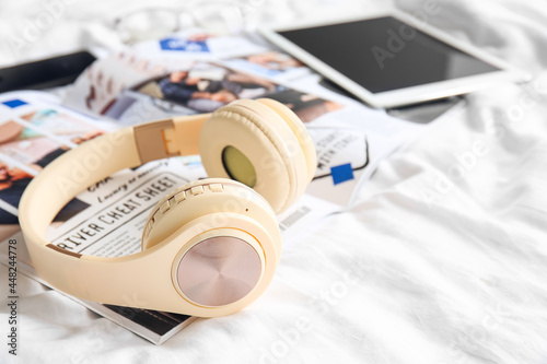 Modern headphones with magazine on bed, closeup