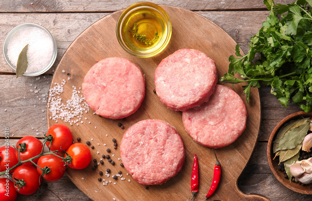 Composition with raw cutlets made of fresh forcemeat on wooden background Composition with raw cutlets made of fresh forcemeat on wooden background