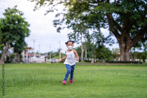Small girl with protective ￼ face mask Running at field￼.