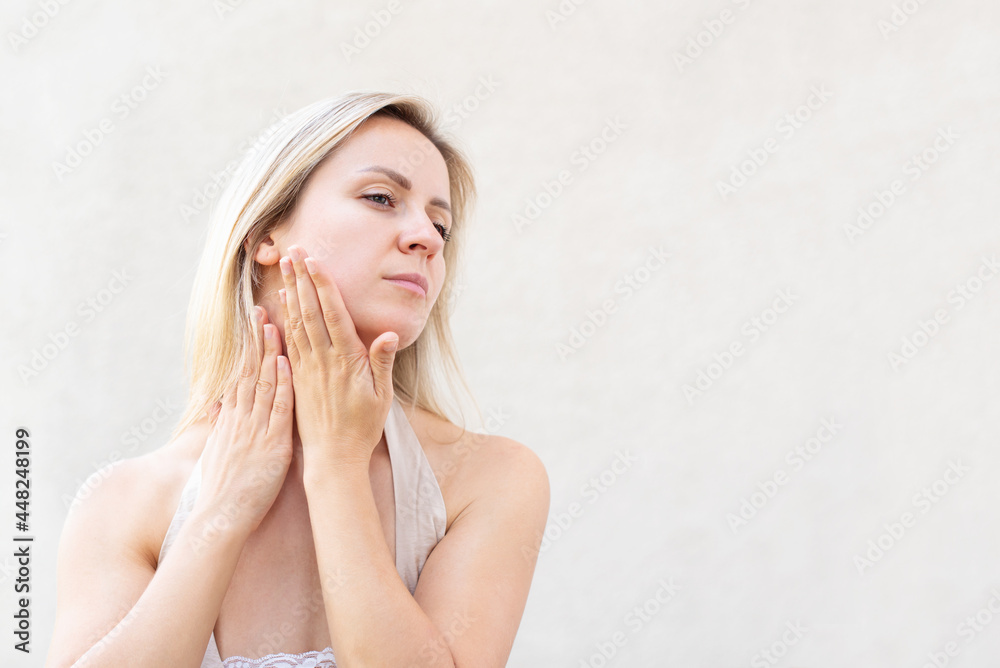 Blonde woman is doing her own facial massage. Concept of anti-aging skincare, non-surgical rejuvenation and self-care, facial gymnastics self massage and rejuvenating exercises face building for skin Blonde woman is doing her own facial massage. Concept of anti-aging skincare, non-surgical rejuvenation and self-care, facial gymnastics self massage and rejuvenating exercises face building for skin