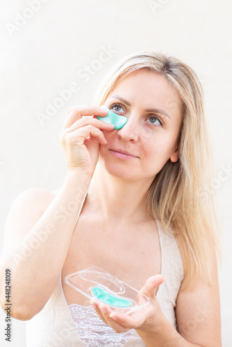 Beauty woman applying eye patches under eyes to reduce wrinkles. Eye skin treatment. Anti - aging collagen hydrogel eyepatch