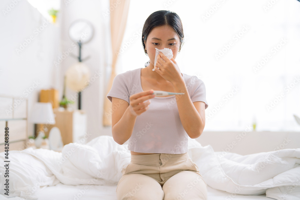 Asian woman she home isolation , she's stressed. She measures her body temperature. Asian woman she home isolation , she's stressed. She measures her body temperature.
