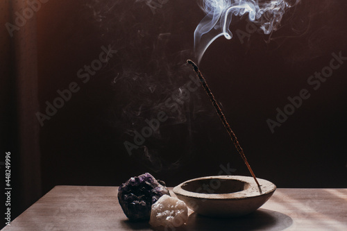 Bild auf Leinwand A stick of incense is burned in a room, it emanates aromatic smoke, it is accompanied by crystals