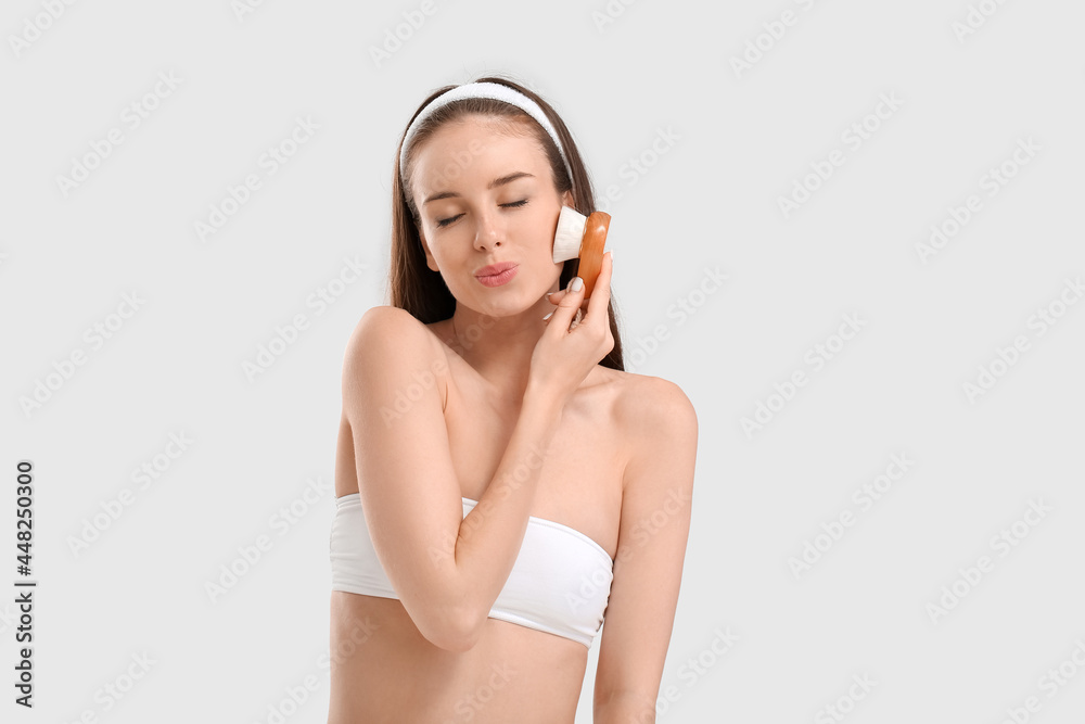 Beautiful young woman with massage brush on light background Beautiful young woman with massage brush on light background
