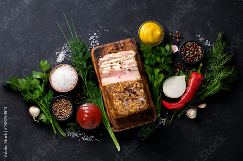 Lard with spices, herbs, mustard and pepper on a wooden board. Ukrainian traditional national cuisine. View from above.
