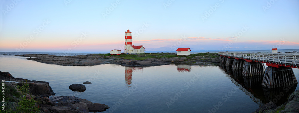 Obraz premium Panoramic view of Pointe-des-Monts Lighthouse at sunset with reflections in the sea, Cote-Nord, Quebec