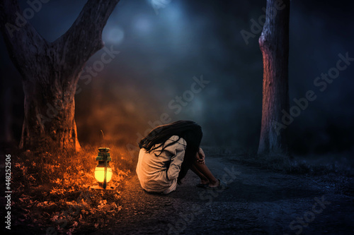 Bilde på lerret A little girl wanders through the forest, sitting alone with a lantern