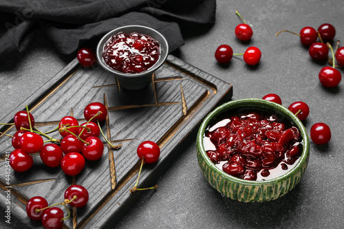 Bowls of tasty cherry jam on dark background