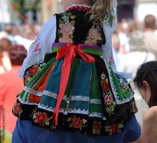 Girl child in traditional folk costume from Lowicz region in Poland on her fathers back while join Corpus Christi procession