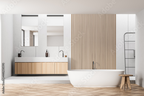 White bathroom with partition, wood details and rounded tub photo