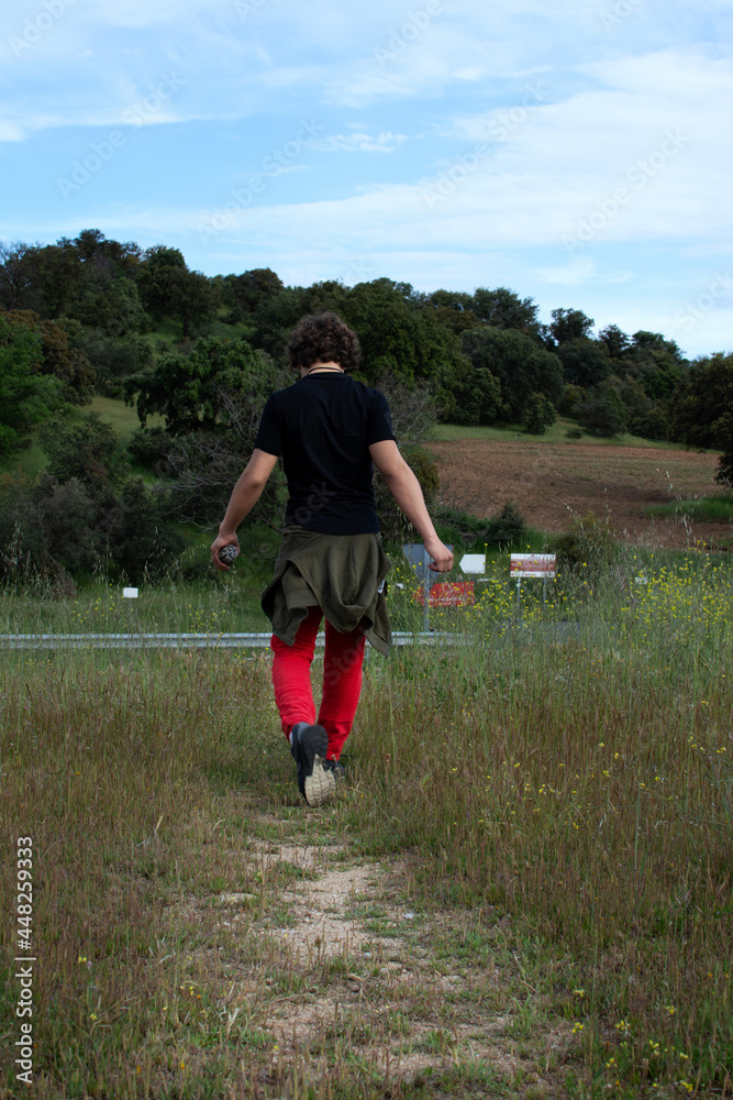Teenager walking along a path with flowers and plants on the sides. Teenager walking along a path with flowers and plants on the sides.