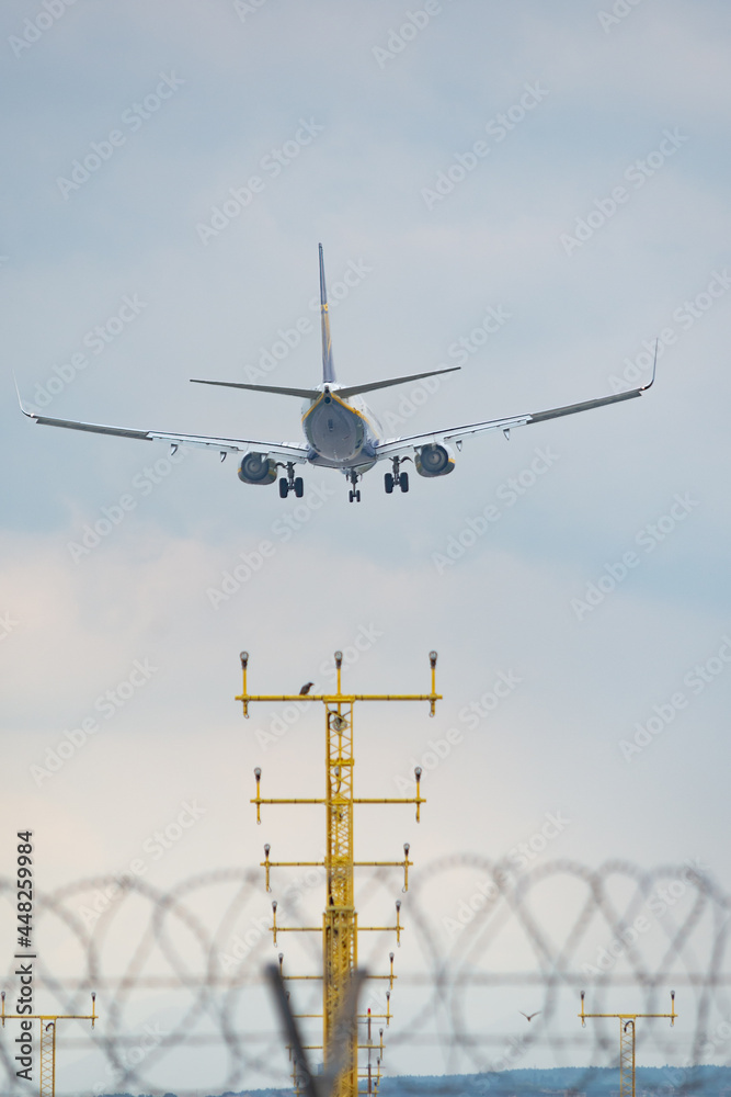 Aircraft is landing on the airstrip of Milan Malpensa Airport, Italy. Wings, fuselage and engine are visible. Sky with clouds in the background. Aircraft is landing on the airstrip of Milan Malpensa Airport, Italy. Wings, fuselage and engine are visible. Sky with clouds in the background.