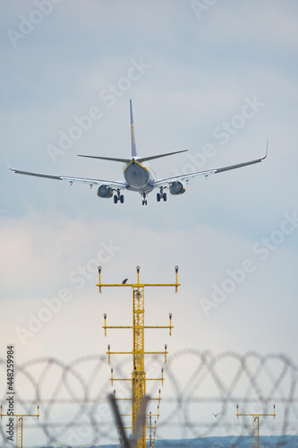 Aircraft is landing on the airstrip of Milan Malpensa Airport, Italy. Wings, fuselage and engine are visible. Sky with clouds in the background.