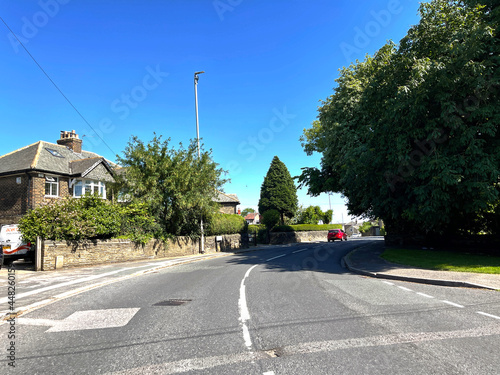 View along, Uppermoor with houses, trees, and a blue sky in, Pudsey, Leeds, UK