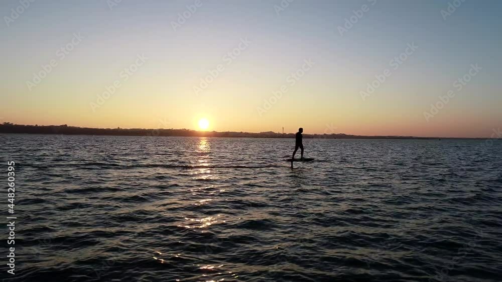 E Foil Sunset boating on the water. Paddleboard, stand-up surfing on electric foil. Aerial drone shot at sunrise. Luxury lifestyle, superyacht water toys.