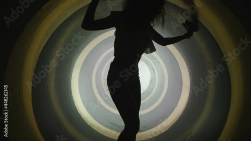 A silhouette of beautiful sexy girl , woman dancing inside round circle tube . Against colored & gray background . Real decoration . None computer graphics . Shot on Arri Alexa Cinema Camera in 4K .
