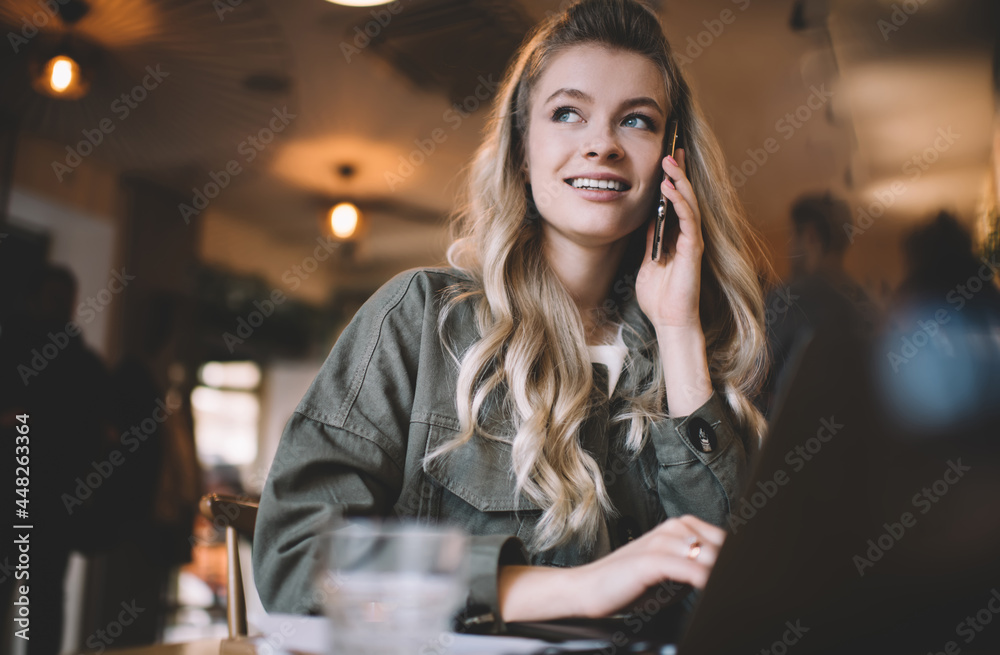 Woman working on computer and talking on phone in cafe Woman working on computer and talking on phone in cafe