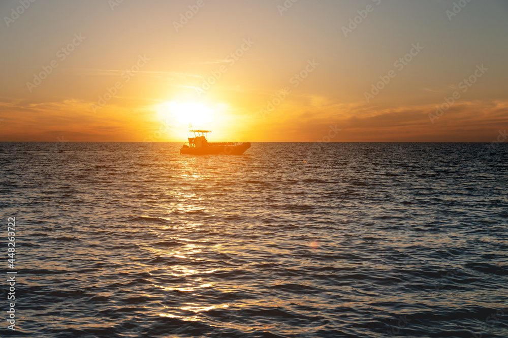 Small fishing boat catamaran at sunset. Sea transport without people in the sunset light. Twilight at sea