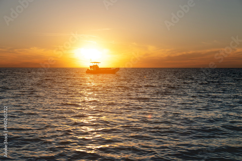 Small fishing boat catamaran at sunset. Sea transport without people in the sunset light. Twilight at sea © yanik88
