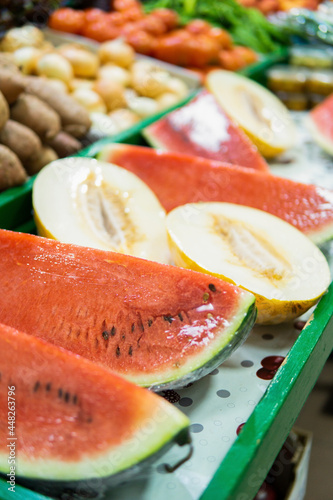 Vertical view of watermelon and melon portions displayed in a traditional food market.