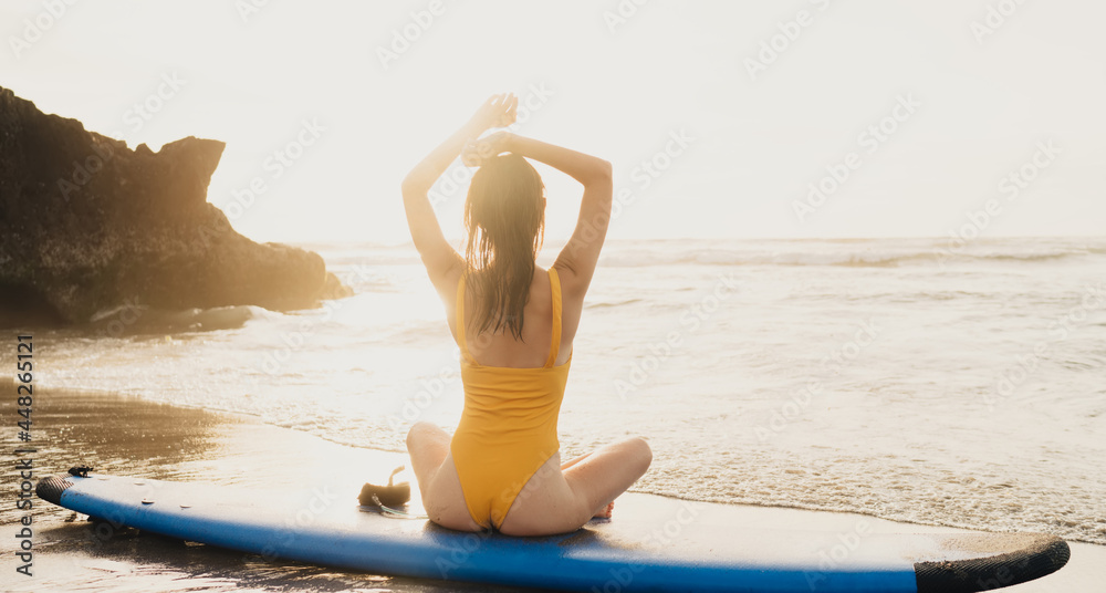 Faceless surfer on surfboard contemplating wavy ocean in summer