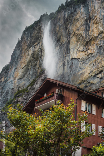Lauterbrunnen valley, Switzerland. Swiss Alps. Cozy small house in mountains, waterfall. Forest and rocks. Beautiful landscape, Europe.