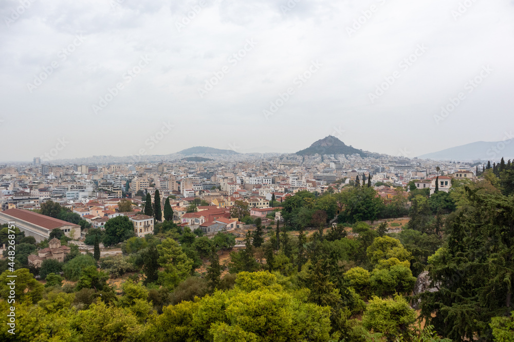 View on mount Lycabettus and Athens old city center architecture in vivid greenery in gray foggy day from Areopagus - Hill near Acropolis