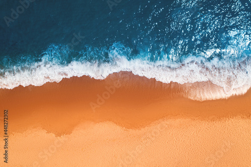 Aerial top view from drone of sandy beach with turquoise sea waves with copy space for text