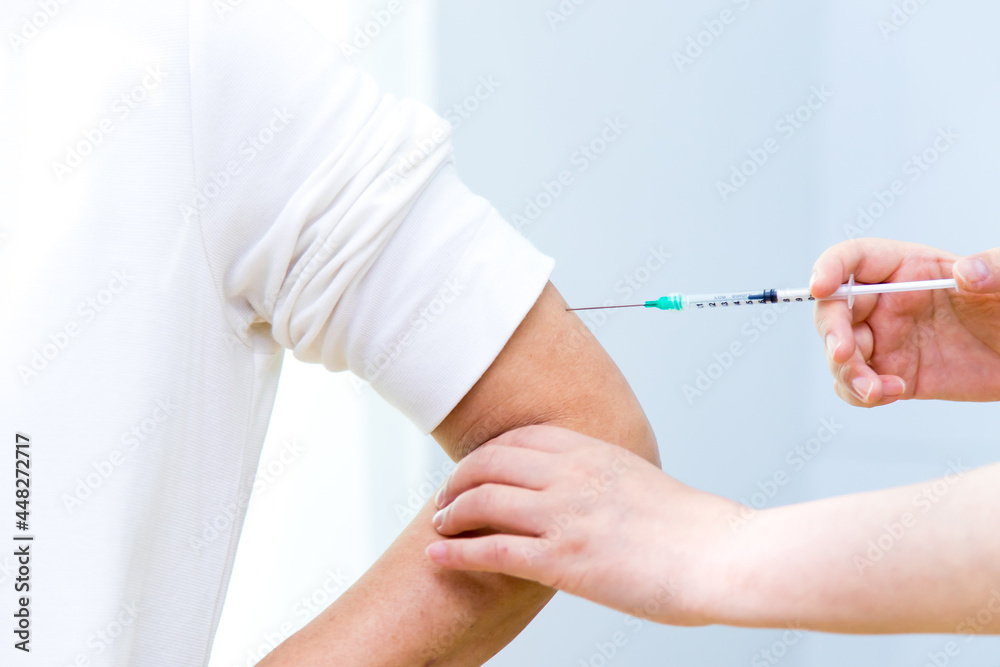 Nurse holding syringe making vaccination injection in shoulder of female patient. Flu influenza vaccine clinical trials concept, corona virus treatment side effect, inoculation. Nurse holding syringe making vaccination injection in shoulder of female patient. Flu influenza vaccine clinical trials concept, corona virus treatment side effect, inoculation.