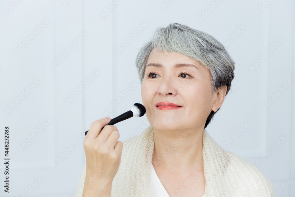 Senior Asia woman is holding a makeup brush. Senior Asia woman is holding a makeup brush.