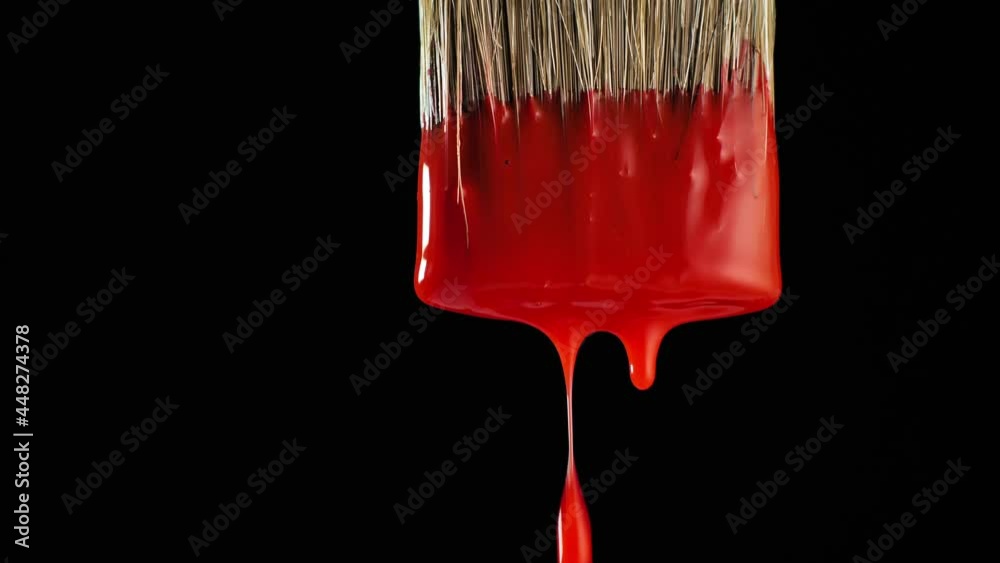 Red paint drips from a wide brush.
