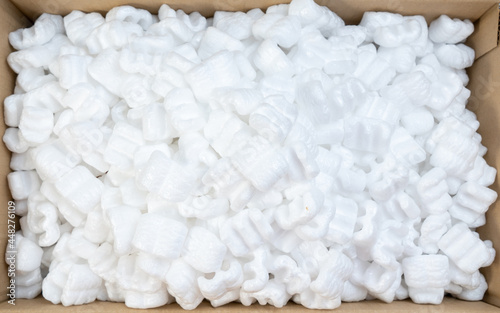 Top view of white polystyrene foam in parcel box. Polystyrene foam cushioning material for packaging, A cardboard box with packing foam pellets.