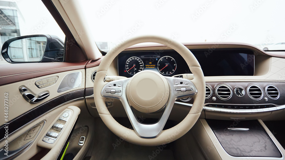 Car interior luxury. Interior of prestige modern car. Leather comfortable seats, dashboard and steering wheel. White cockpit with exclusive wood and metal decoration