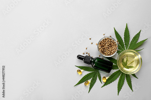 Flat lay composition with CBD oil or THC tincture and hemp leaves on light background, space for text