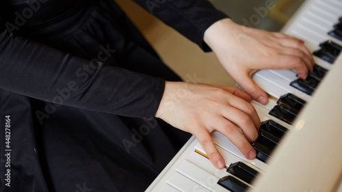 Womans hands on the keyboard of the piano closeup