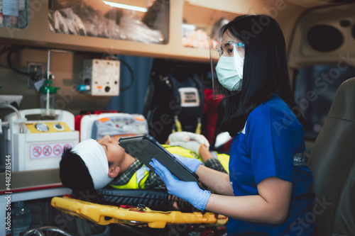 Doctor/nurse uses a tablet to check information of injured patients in an accident at work. while taking the injured person to the hospital by ambulance. Construction worker injured in a work accident