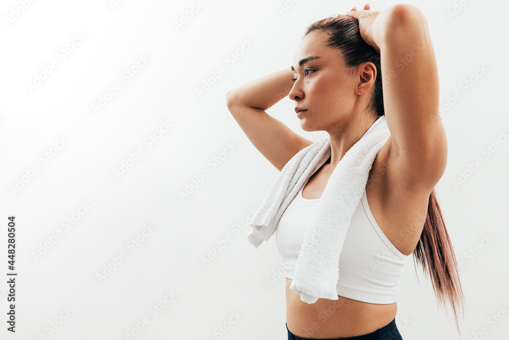 Portrait of an Asian woman relaxing during a workout. Tired sportswoman with white towel on neck. Portrait of an Asian woman relaxing during a workout. Tired sportswoman with white towel on neck.