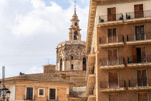 Valencia's famous Miquelet tower looming through some buildings, and with the blue cloudy sky in the background.  photo