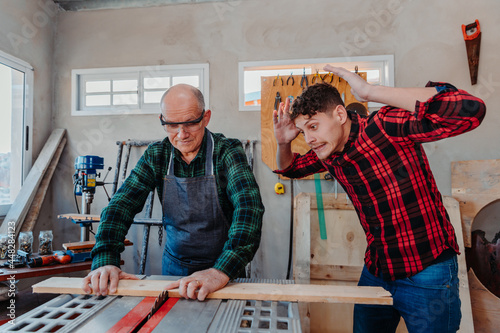 Tableau sur toile father and son in their carpentry workshop, danger, misuse of tools