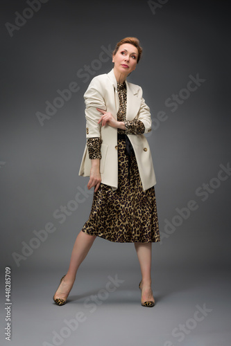 full length portrait of a fashionable aged woman isolated on grey